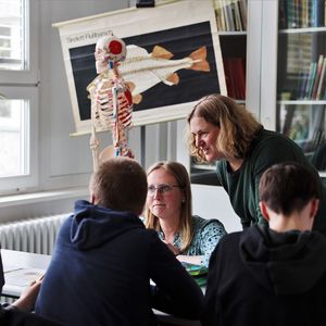 Two scientists working in groups with three pupils