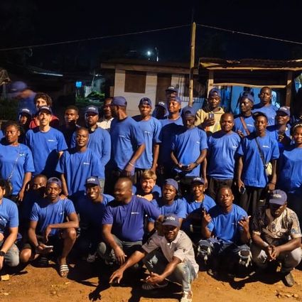 Photo de groupe d’une équipe en t-shirts bleus lors d’un événement en plein air en soirée.