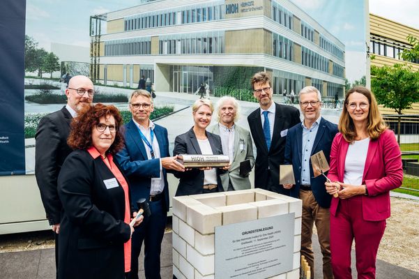 Gruppenfoto von acht Personen hinter einem Grundstein