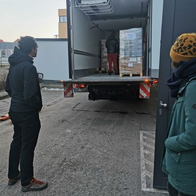 Transporter mit Material und drei Helfer*innen 